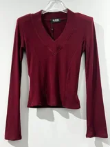 Remera de manga larga color negro, con escote en V y mangas acampanadas tipo Oxford. Confeccionada en tejido de algodón elastizado, con un diseño entallado al cuerpo.