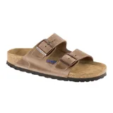 Sandalia Birkenstock modelo Arizona de dos correas ajustables con hebillas metálicas. Presenta capellada de cuero engrasado, plantilla anatómica de corcho y suela de goma antideslizante.