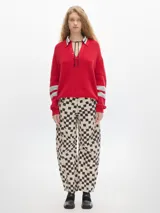 Sweater rojo de punto con cuello polo blanco a rayas azules y mangas largas con rayas grises en los puños.