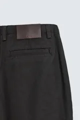 Pantalón de corte wide fit confeccionado en algodón con efecto lavado. Presenta pliegues frontales, bolsillos laterales y bolsillos traseros de vivo. Cierre frontal con cremallera y gancho metálico oculto.