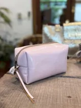 Neceser de cuero con acabado brillante, cierre superior y tirador de cuero con detalle de cinta estampada.