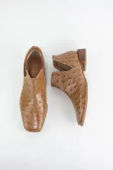 Botin de cuero con grabado tipo avestruz, color marrón, con aberturas laterales y taco bajo cuadrado.