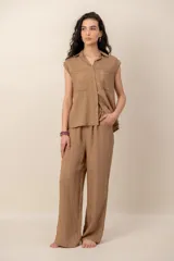 Conjunto compuesto por una blusa sin mangas con cuello camisero, bolsillos frontales y cierre de botones, y un pantalón largo de corte recto y holgado, ambos confeccionados en tejido texturizado de color marrón.