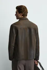 Cazadora regular fit de cuero marrón con efecto lavado vintage, cuello camisero, cierre frontal de cremallera y bolsillos de vivo en la cadera.