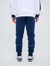Pantalón de jogging azul marino Umbro del Club Nacional de Football, con cordón ajustable en la cintura, puños elastizados en los tobillos y bandas laterales en tonos de azul. Cuenta con el escudo del club en una pierna y el logo de la marca en la otra.