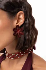 Aro de gran tamaño en forma de flor, color bordó con acabado brillante y detalle de glitter en el centro.