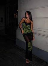 Vestido largo de microtul negro con estampado de flores grandes en tonos verdes. Presenta breteles finos, escote redondo y diseño ajustado al cuerpo con transparencias.