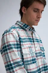 Camisa de manga larga a cuadros en tonos blanco, verde, azul y rojo. Tiene dos bolsillos en el pecho y cierre con botones.