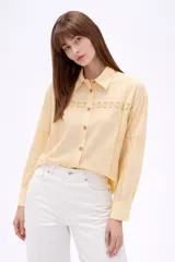 Camisa de algodón color blanco, de corte holgado y manga larga. Presenta detalles de encaje tipo puntilla en el frente, espalda y mangas, con cierre frontal de botones y cuello camisero clásico.