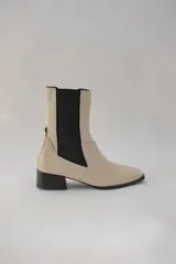 Botines Chelsea color beige con elástico lateral negro y tacón bajo cuadrado.