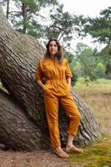 Mono color ocre de gabardina 100% algodón, con corte clásico, cierre frontal completo, pantalón largo con bolsillos, manga corta y cintura fruncida en la espalda.