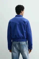 Sobrecamisa regular fit de Zara, confeccionada en pana de algodón color azul con efecto lavado. Cuenta con cuello solapa, manga larga con puño y botón a presión, bolsillos frontales de plastrón con solapa y cierre de cremallera.