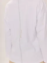 Remera blanca de manga larga con cuello alto, corte holgado y costuras verticales decorativas en el frente.