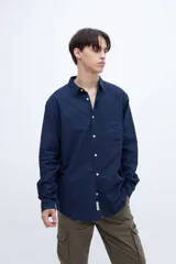 Camisa celeste de algodón, corte regular fit, con cuello solapa clásico, manga larga, bolsillo en el pecho y botones personalizados.