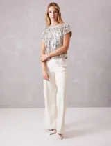 Blusa de manga corta cubierta de lentejuelas en tono champagne, con cuello redondo a la base y forro interno a tono.