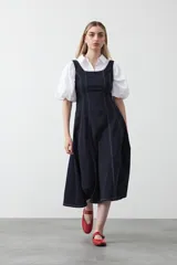 Vestido midi sin mangas de color azul oscuro, con escote cuadrado y silueta evasé. Presenta costuras a contratono en color blanco que recorren verticalmente el diseño, aportando estructura y un detalle gráfico. Confeccionado en tejido con cuerpo y caída firme.