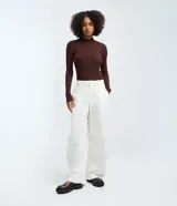 Blusa rectilínea de punto ligero en color beige, de manga larga y cuello alto, con diseño acanalado.