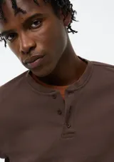 Camiseta Henley de manga larga color marrón, con textura waffle y tapeta de tres botones en el cuello.