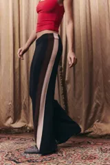 Pantalón tejido de corte recto y holgado, con cintura elástica. Presenta un diseño tricolor en los laterales con franjas verticales en negro, marrón y beige.