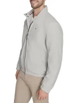 Campera tipo bomber de Tommy Hilfiger en color gris claro. Presenta cierre frontal completo, cuello mao con detalles internos distintivos de la marca, puños y ruedo elásticos, y el logo de la bandera bordado en el pecho.