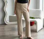 Pantalón tipo palazzo de tejido de punto acanalado en color beige, con cintura elástica y cordón ajustable.