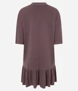 Vestido tipo camiseta de algodón, color malva o ciruela con efecto lavado, de corte recto y holgado, con cuello redondo y mangas cortas. Presenta un volado fruncido en el bajo.