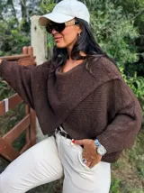 Sweater de punto gris con diseño cruzado en el frente, mangas largas con puños ajustados y corte holgado.