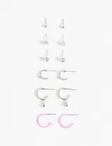 Set de caravanas plateadas con diferentes diseños: aros tipo argolla con dije colgante, aros tipo argolla con strass, aros tipo argolla esmaltados en rosa y aros tipo botón con detalles de strass y esmalte.