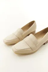 Mocasines de cuero vacuno color beige con textura efecto cocodrilo, punta cuadrada y taco bajo.