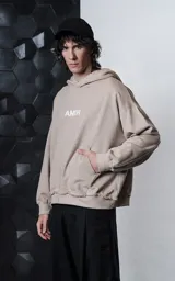Hoodie oversize color gris topo, confeccionado en rústico de algodón, con capucha forrada, bolsillo canguro y costuras expuestas en mangas y ruedo. Presenta estampa gráfica en la espalda con la palabra AMOR y diversos motivos románticos.