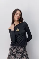 Remera de manga larga negra con calce al cuerpo y escote amplio tipo bote que deja los hombros al descubierto.