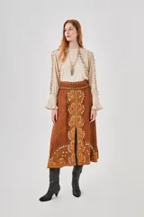 Falda larga marrón con estampado central de motivos florales en tonos naranjas y blancos, y pequeños puntos blancos distribuidos por toda la tela.