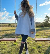 Canguro gris claro con cuello alto, mangas largas con puños en gris oscuro, bolsillo tipo canguro y corte holgado.