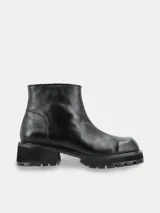 Bota de caña corta marca Pastiche, confeccionada en cuero negro con punta cuadrada y suela de goma tipo track con taco cuadrado.