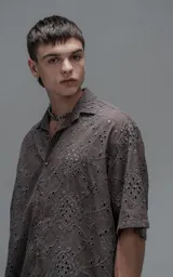 Camisa de manga corta con calce oversize y cuello abierto, confeccionada en algodón con diseño de bordado tipo broderie y efecto de desgaste en el color.