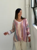 Sweater de punto con diseño abstracto en tonos rosados, beige y azul, de corte holgado, cuello en V y mangas largas con puños vueltos.