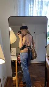 Top negro de estilo halter con espalda descubierta y tiras ajustables para atar. Confeccionado en tejido elástico, presenta un diseño versátil y moderno.
