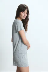 Conjunto de pijama de dos piezas, compuesto por una remera de manga corta y un short, ambos en tela gris jaspeada con estampado de pequeñas flores blancas.