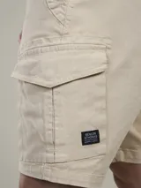 Bermuda cargo color marrón camel, confeccionada en twill con spandex, de calce cómodo y tiro medio. Cuenta con bolsillos laterales con solapa y bolsillos traseros con botón.