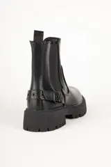Botas de caña baja color negro, símil cuero, con pieza elastizada en sus laterales, aplique de hebilla metálica y plataforma de 5cm de alto.