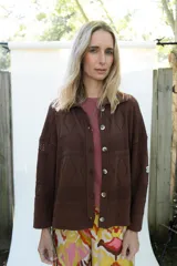 Cardigan de punto color marrón, abierto con botones imitación hueso, manga larga con parche bordado y diseño texturado.