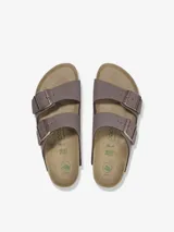 Sandalia tipo slide de dos tiras ajustables, color marrón topo, con hebillas metálicas color oro rosa. Presenta una plataforma gruesa de color negro sobre la clásica suela de corcho anatómica de Birkenstock.