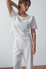 Remera blanca de punto calado con cuello redondo y mangas cortas con terminación ondulada.