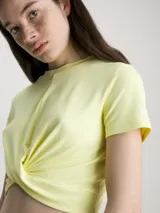 Remera cropped color amarillo pastel, de mangas cortas y cuello redondo. Presenta un panel frontal con twist.