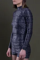 Remera polera de manga larga negra con estampado de letras en gris oscuro, confeccionada en lycra ajustada al cuerpo.
