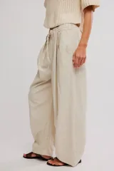 Pantalon de lino y algodon color beige, de tiro bajo, estilo relajado con cintura elastizada ajustable mediante cordón y bolsillos laterales.