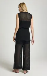 Pantalón calado negro de Le Lis Blanc, con tejido de punto transparente, corte ancho y cintura asimétrica con superposición frontal.