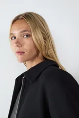 Campera corta negra con cierre frontal metálico, cuello camisero y mangas largas.