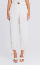 Pantalón rosado de tiro alto con cintura estructurada y hebilla metálica decorativa, diseño fluido de corte relajado con pliegues frontales y ajuste con cordón en los tobillos.