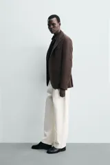Blazer de corte regular fit confeccionado en tejido de lana, con cuello de solapas de muesca, manga larga con puños abotonados, bolsillos de vivo en el pecho y de plastrón en la cadera, cierre frontal de un botón y aberturas en la espalda.